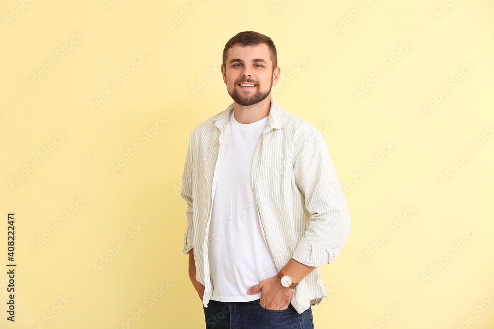 Handsome man with wristwatch on color background