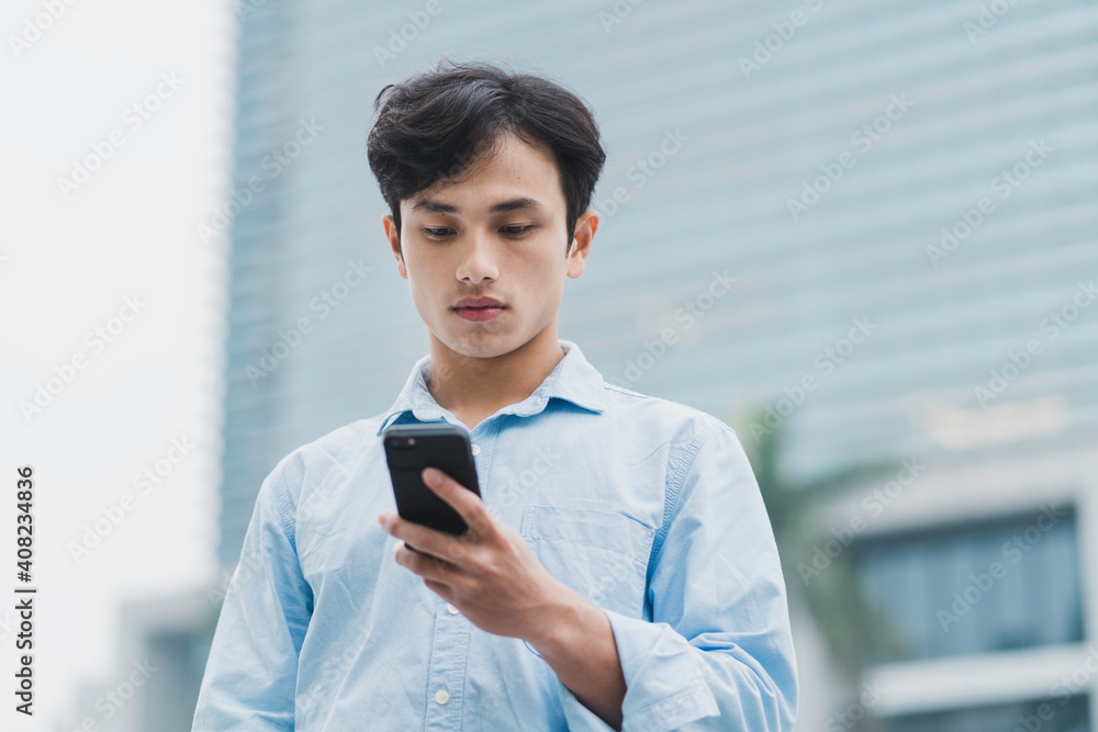 Young Asian man is standing looking at the phone