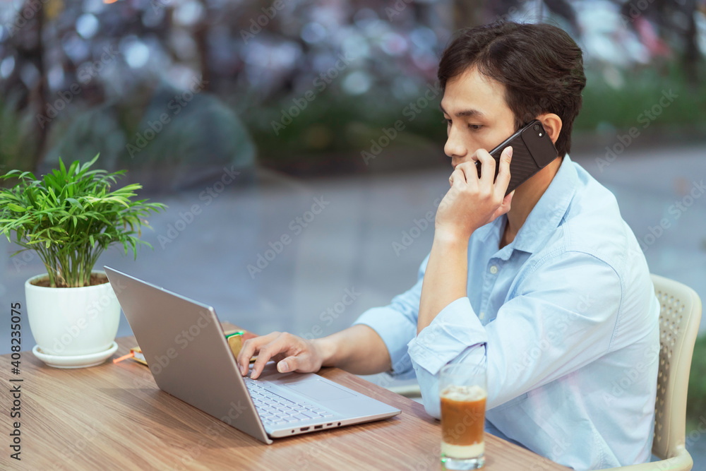 Asian man sitting working alone at a coffee shop

