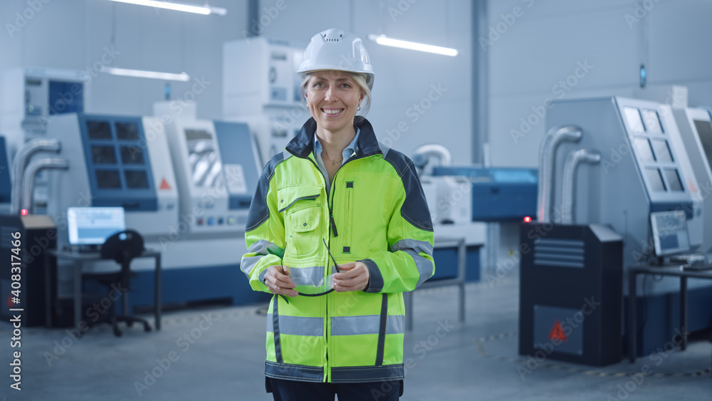 Beautiful Smiling Female Engineer Wearing Safety Vest and Hardhat Holds Safety Goggles. Professional