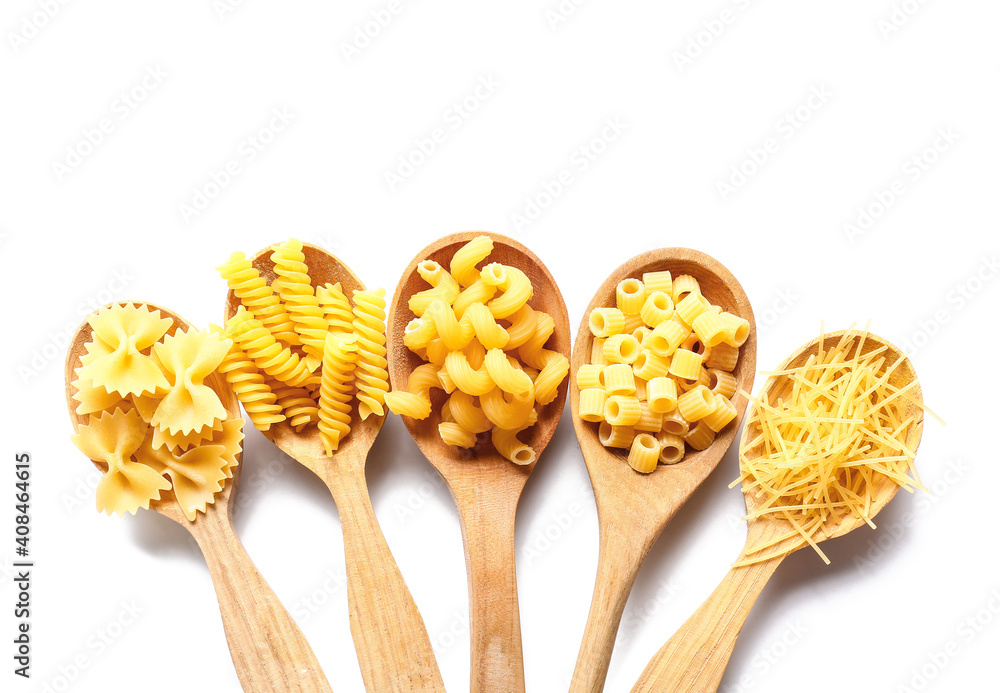 Spoons with assortment of dry pasta on white background