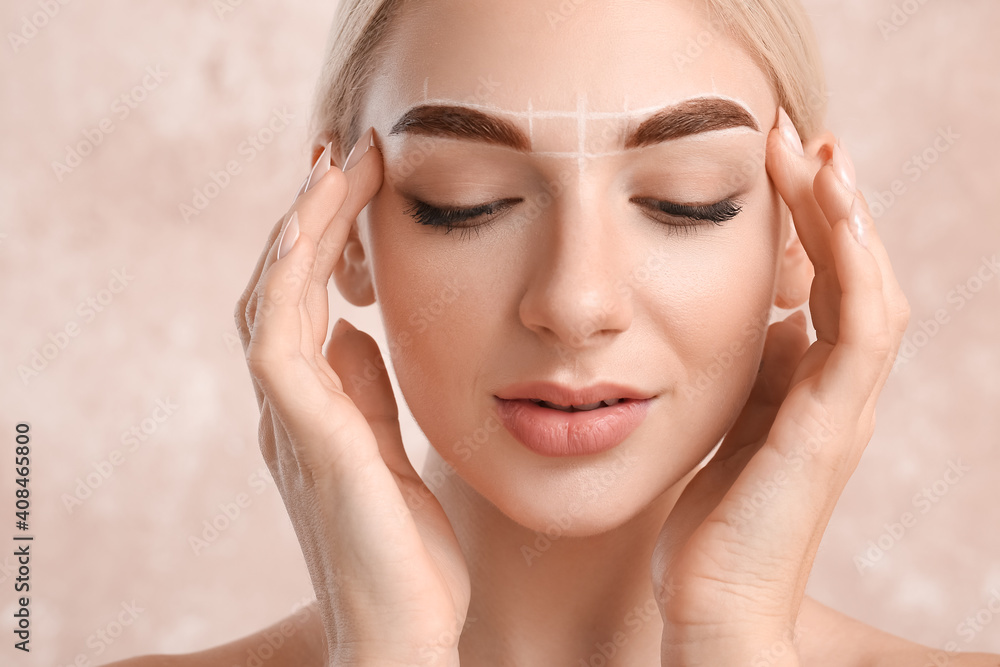 Young woman with marking for eyebrow correction procedure on color background