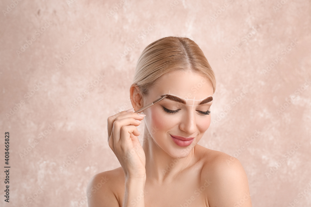 Young woman correcting her eyebrows on color background