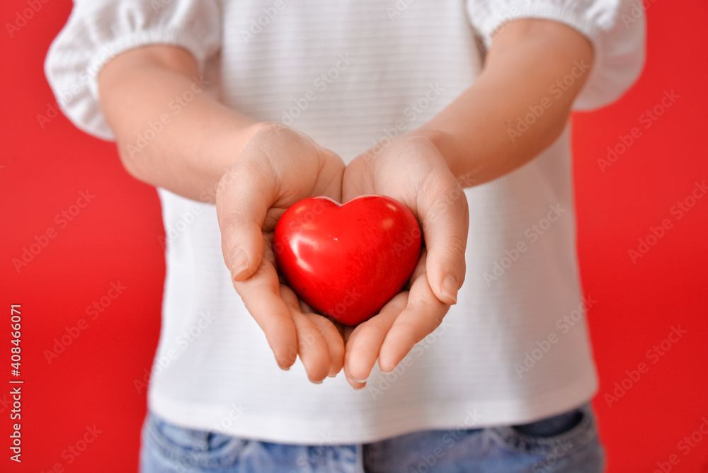 Young woman with red heart on color background, closeup