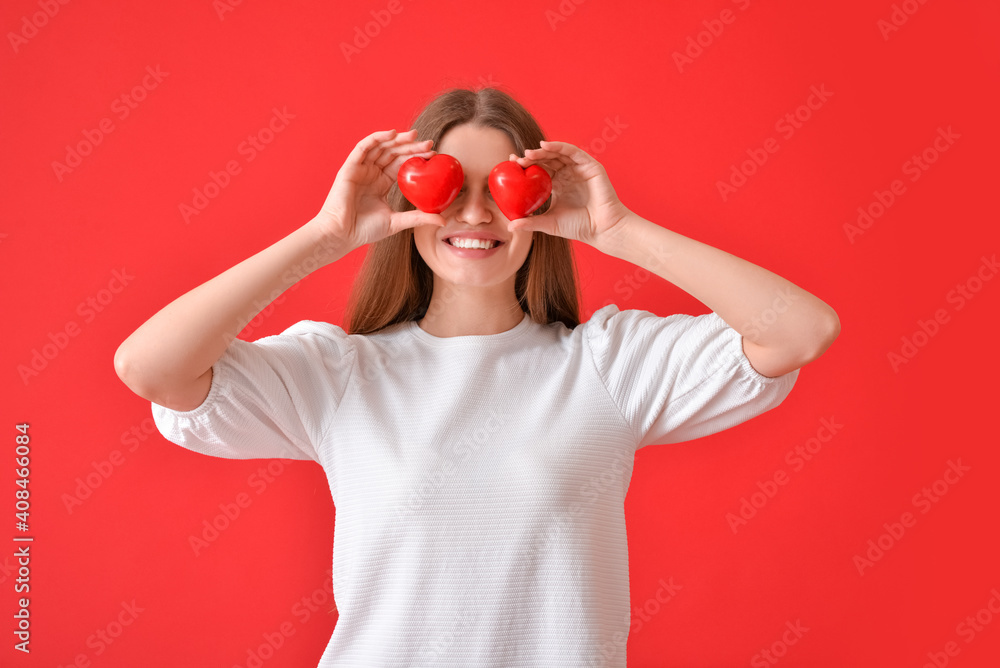 Young woman with red hearts on color background