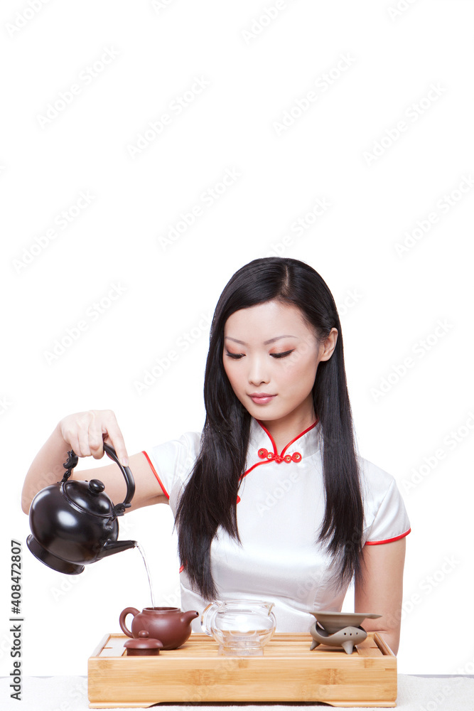 Wearing cheongsam Oriental young woman in preparation for the tea ceremony