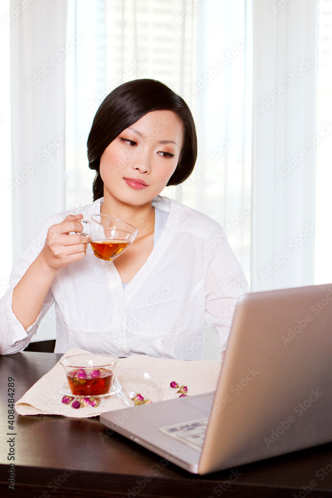 Oriental tea and young woman using a laptop computer