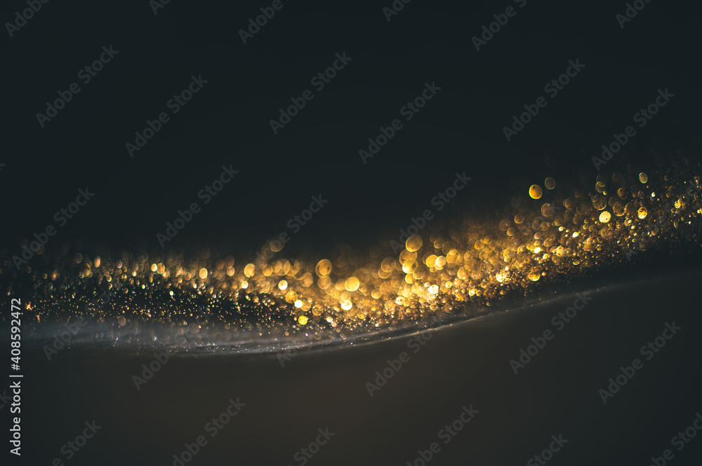 Gold glitter texture on a black background. Golden grainy abstract texture on a black background. De