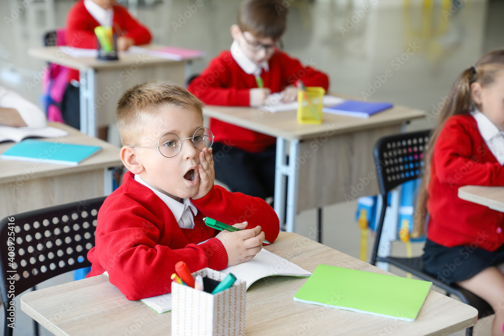 Surprised schoolboy during lesson in classroom