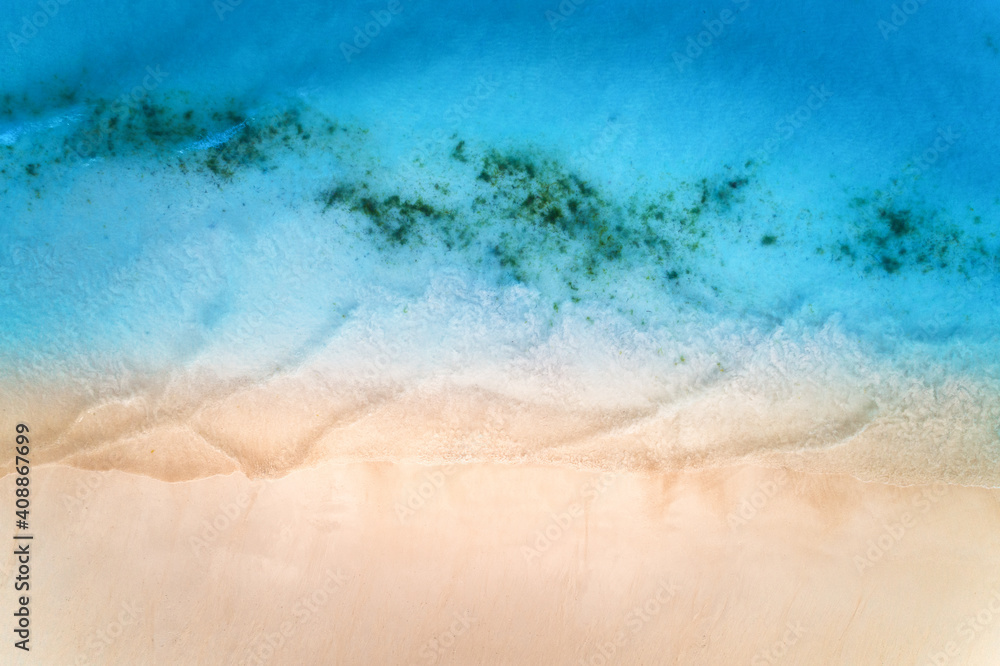 Aerial view of clear blue sea with waves and empty white sandy beach at sunset. Summer in Zanzibar, 