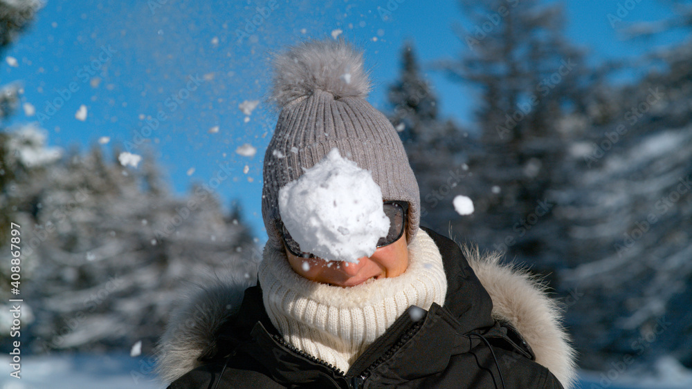 PORTRAIT: Smiling female tourist gets hit in the face by a fluffy snowball.