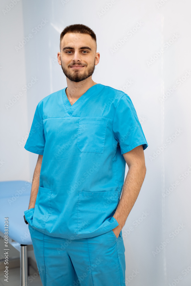 Portrait of a doctor or medical specialist. Modern office background. Man in scrubs stands with hand