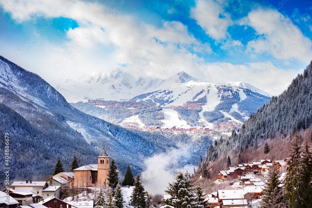 Panorama of Champagny-en-Vanoise village with mist and clouds around old church, over Courchevel res