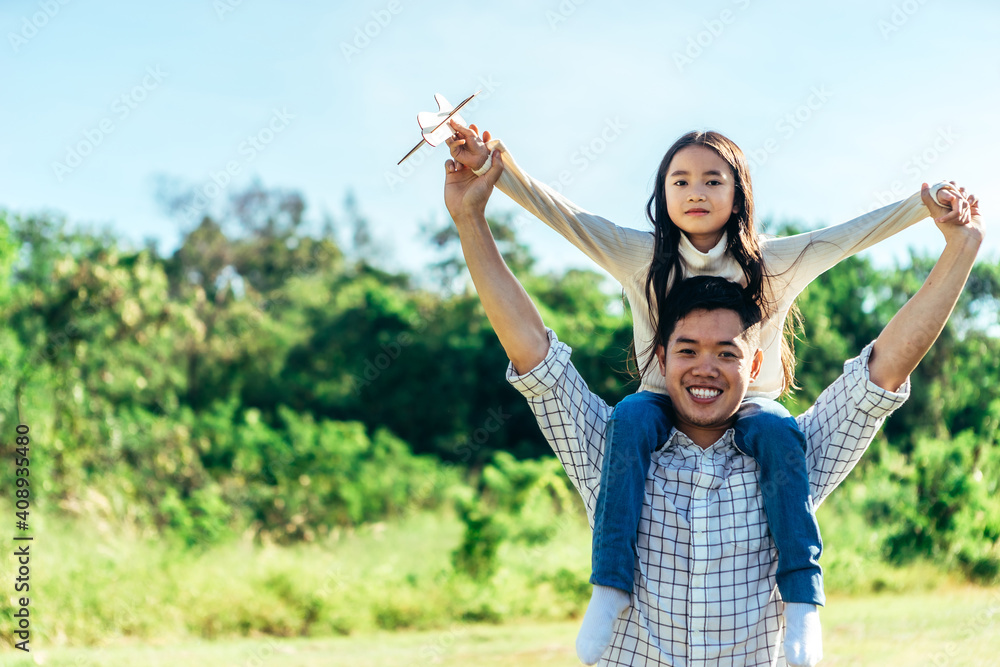 女儿坐在父亲的脖子上。一家人在美丽的自然中度过了一个假期。康塞普