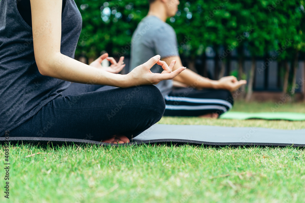 Young Asian couple man and woman practicing yoga in the garden. Summer morning