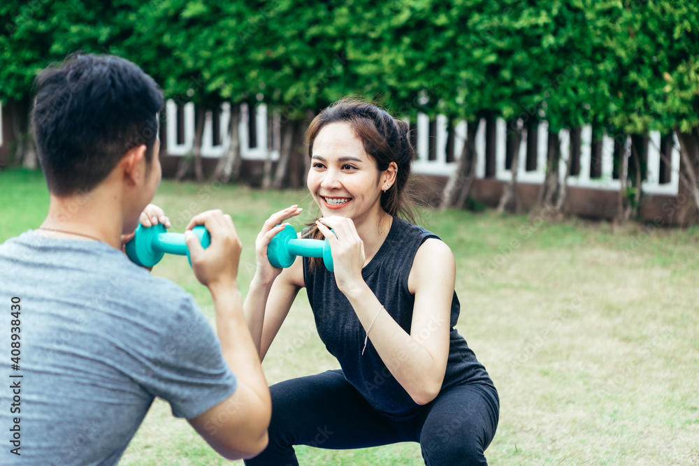 Young Asian couple man and woman practicing yoga in the garden. Summer morning