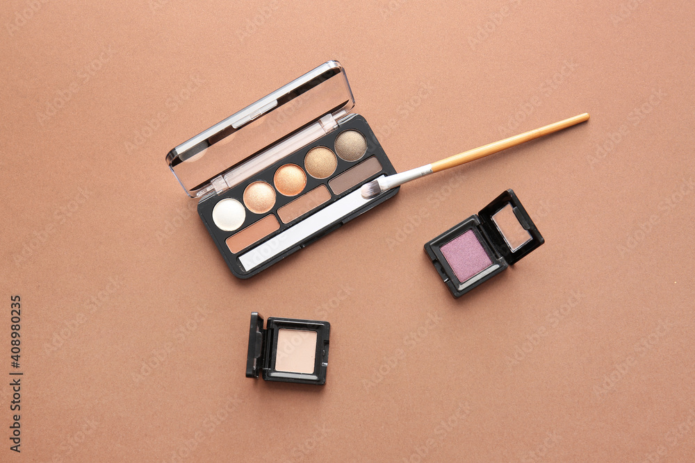 Beautiful palette of eyeshadows and brush  on color background