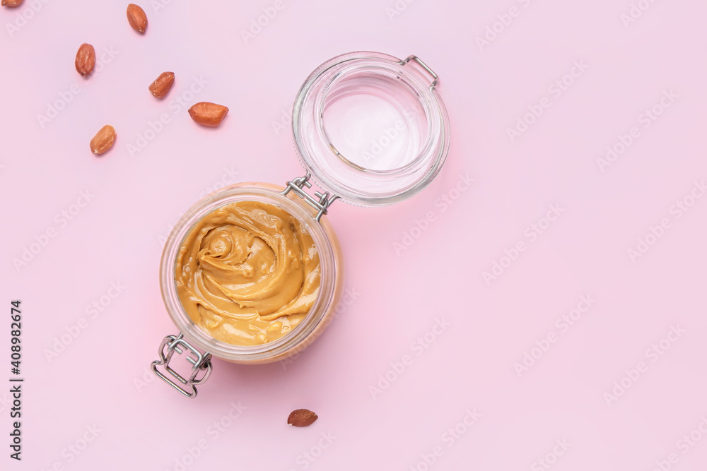 Jar of tasty peanut butter on color background