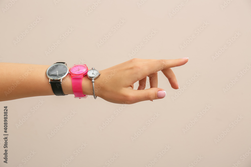 Female hand with stylish wrist watches on light background