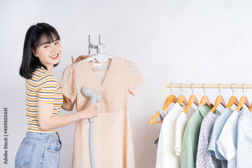 Beautiful Asian woman flattening her dress with the steam iron