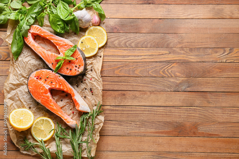 Raw salmon steaks, lemon and herbs on wooden background