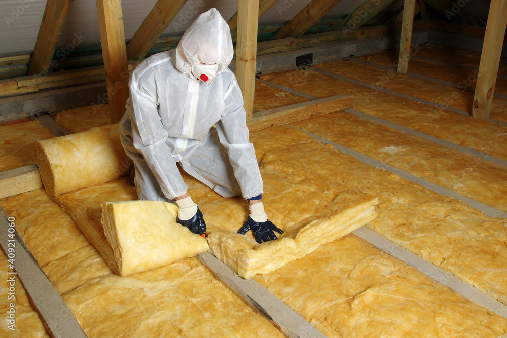 Man installing thermal insulation layer under the roof