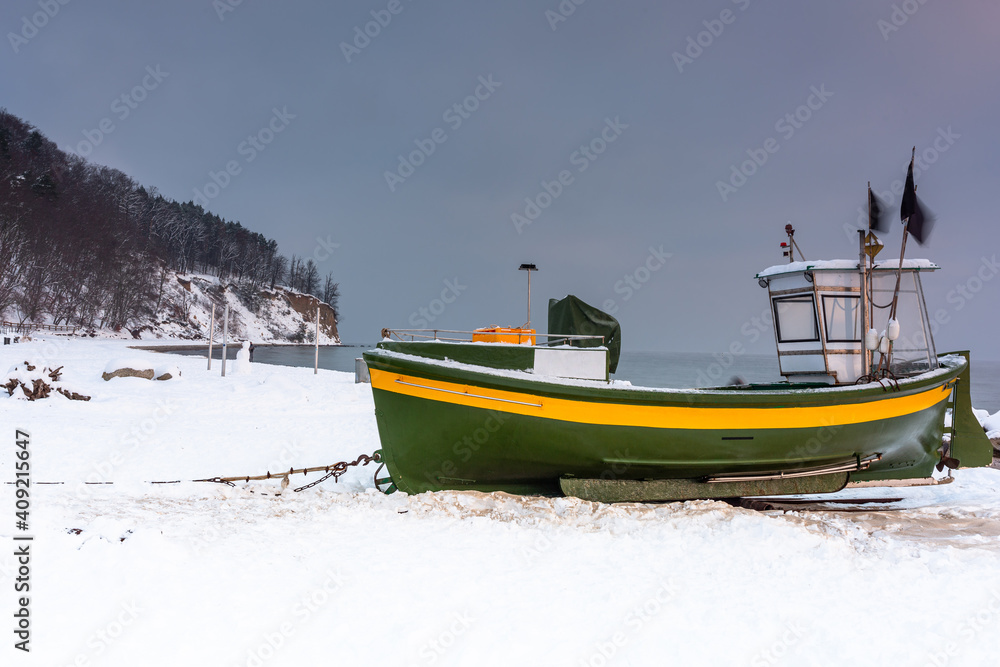 波罗的海日出时，波兰Gdynia Orlowo雪地海滩上的渔船