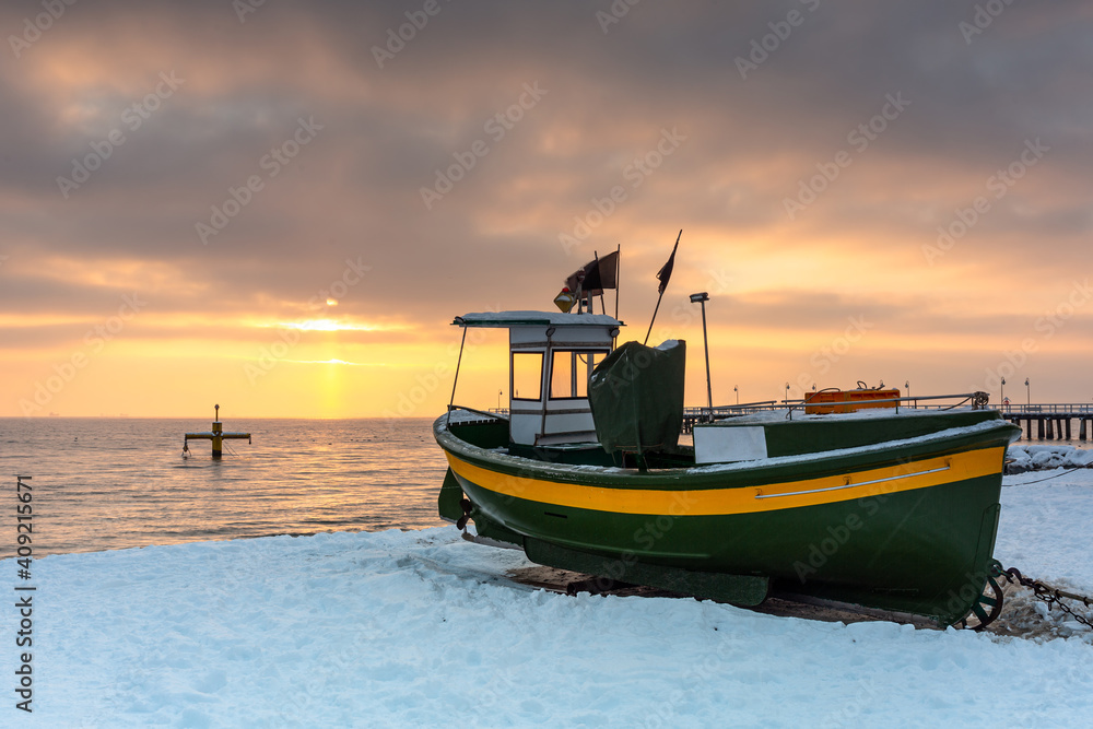 波罗的海日出时，波兰Gdynia Orlowo雪地海滩上的渔船