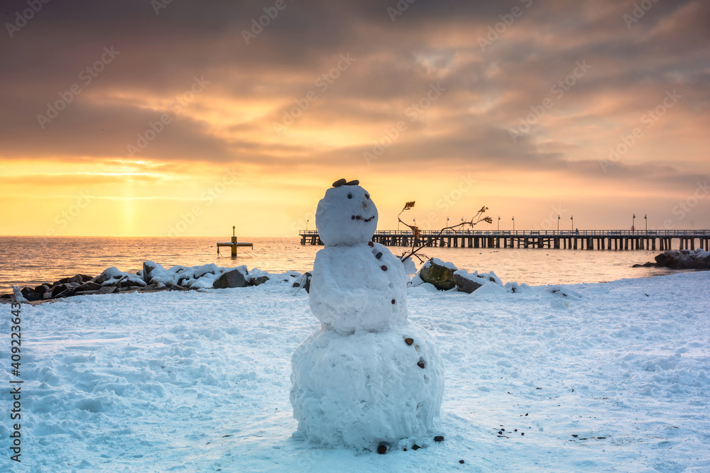 Snowman on the beach of the Baltic Sea in winter at sunrise, Gdynia Orłowo. Poland.