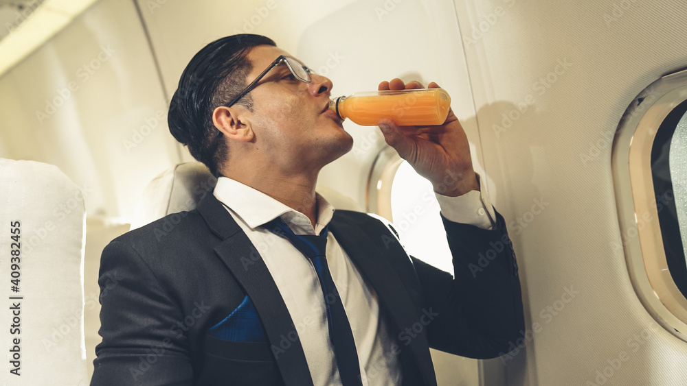 Businessman have orange juice served by an air hostess in airplane . Business trip travel concept .