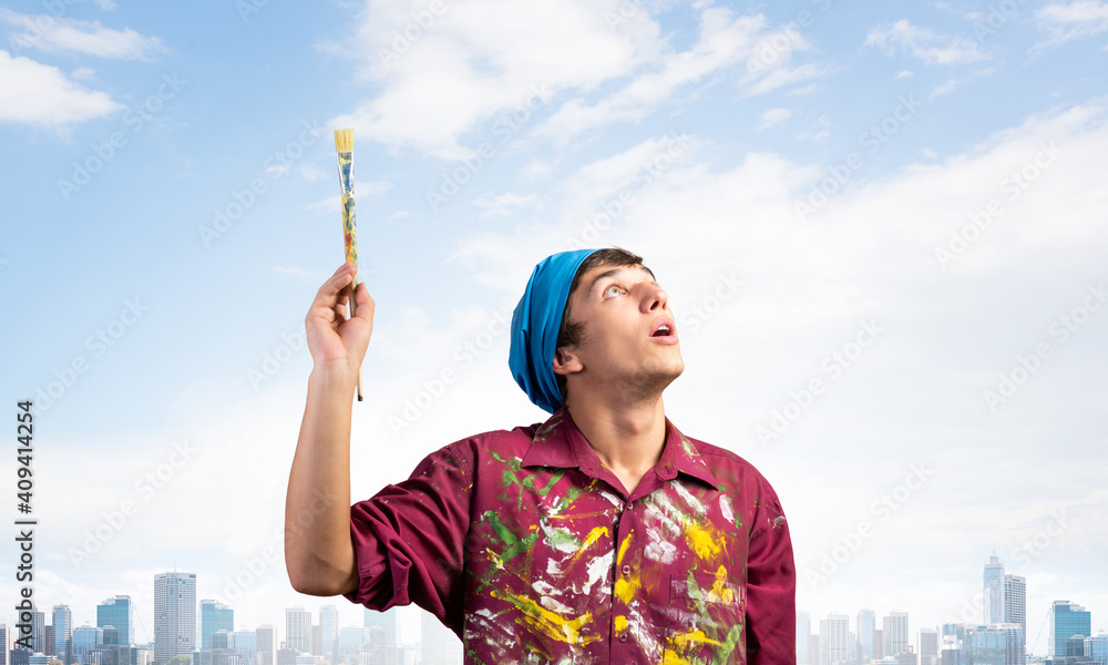 Young painter artist holding paint brush overhead