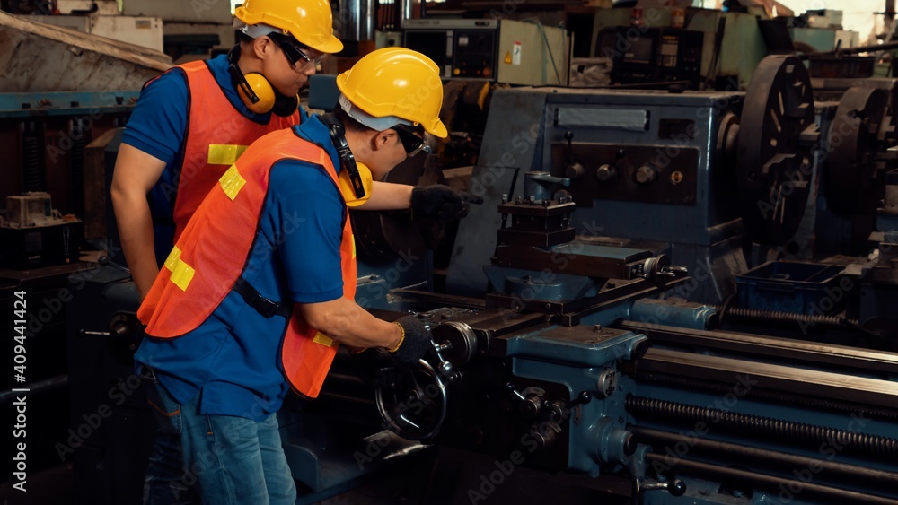 Group of skillful factory workers using machine equipment in workshop . Industry and engineering peo