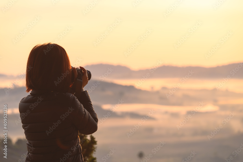 Asian female photographing misty landscape in morning spend vacation in Khao Kho hill Thailand