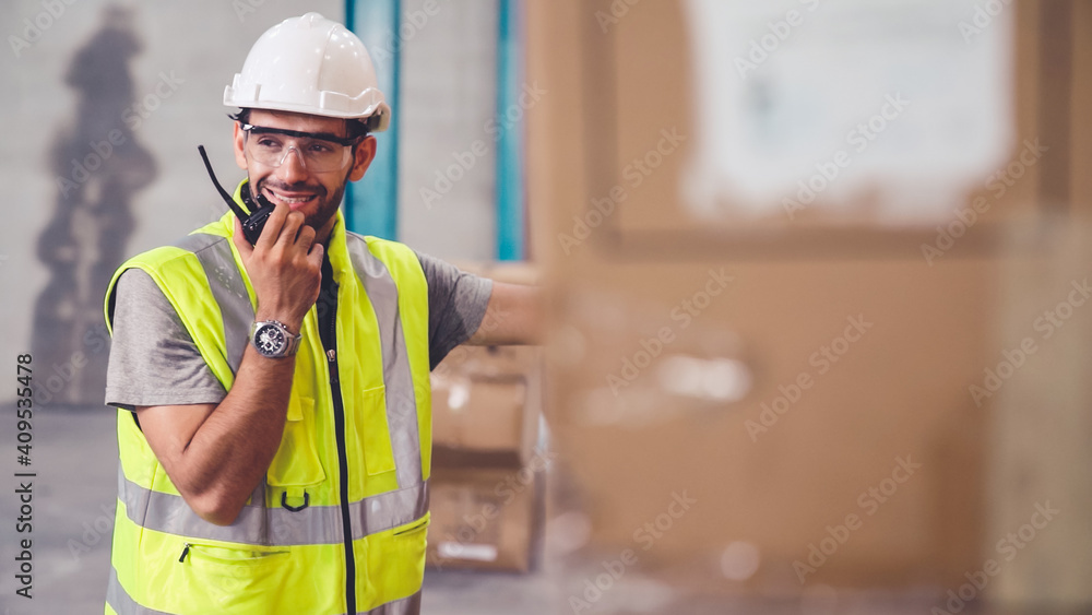 Professional cargo worker talks on portable radio to contact another worker . Factory and warehouse 