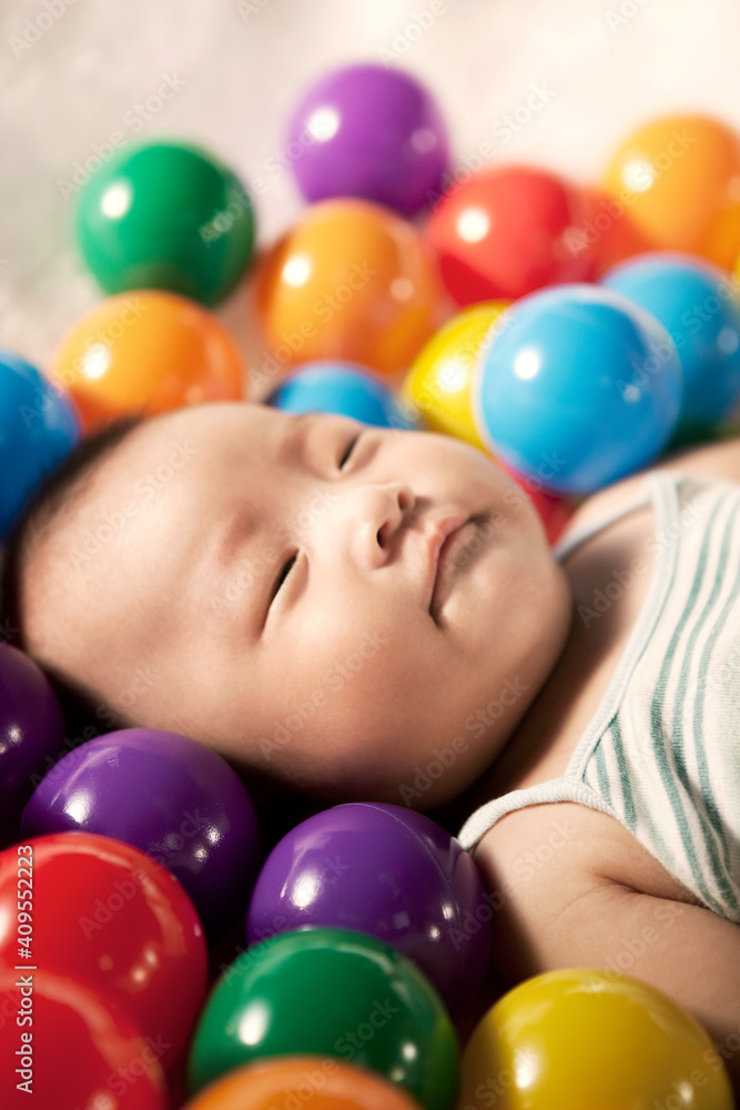 A baby boy surrounding by color balls