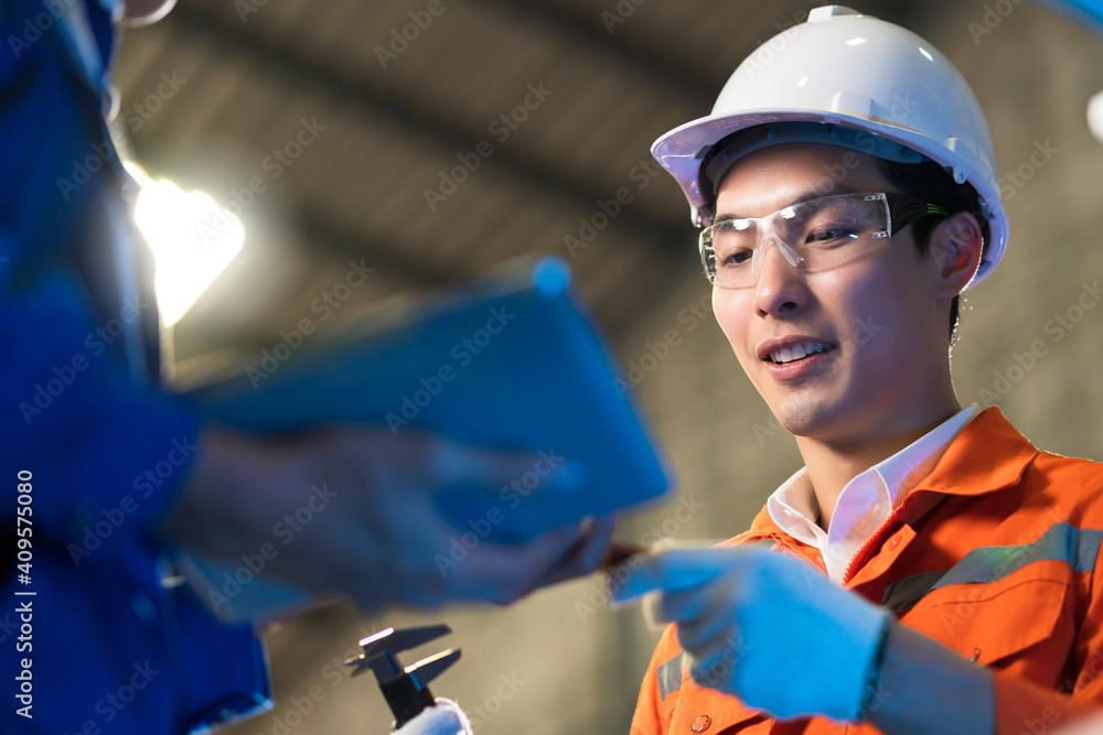 Male Asian engineer professional  having a discussion standing by the machine in the factory ,two as