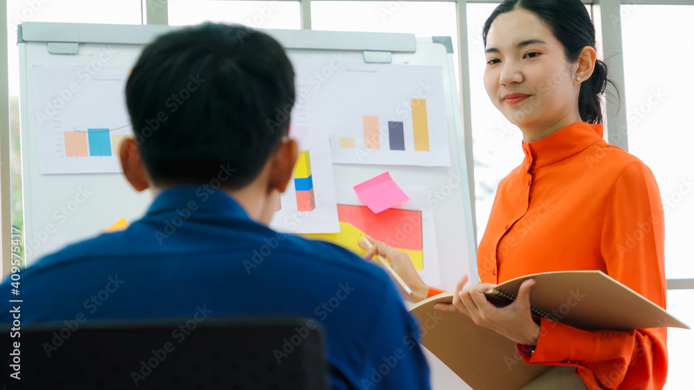 Young woman explains business data on white board in casual office room . The confident Asian busine