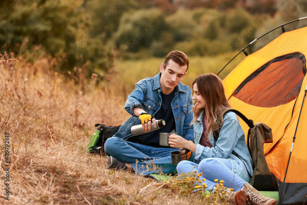 Couple of young tourists near tent in countryside