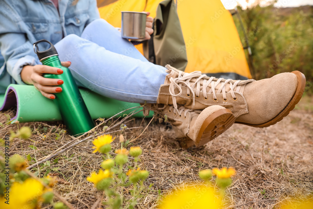 Young female tourist sitting near tent in countryside