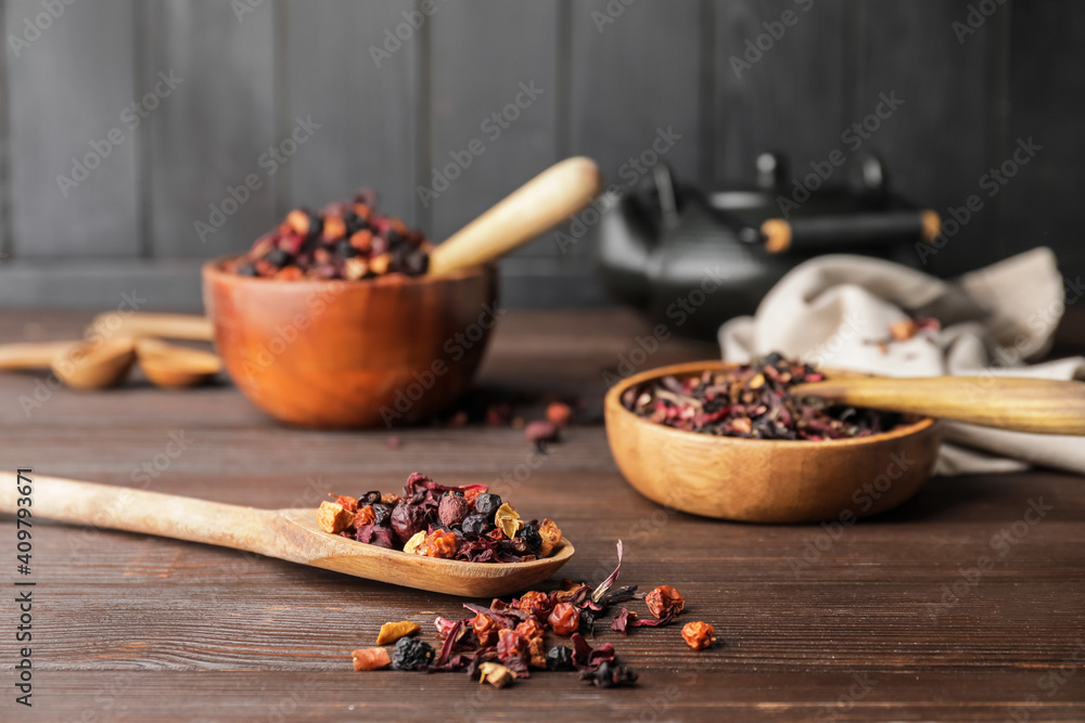 Spoon and bowl with dry fruit tea on wooden background