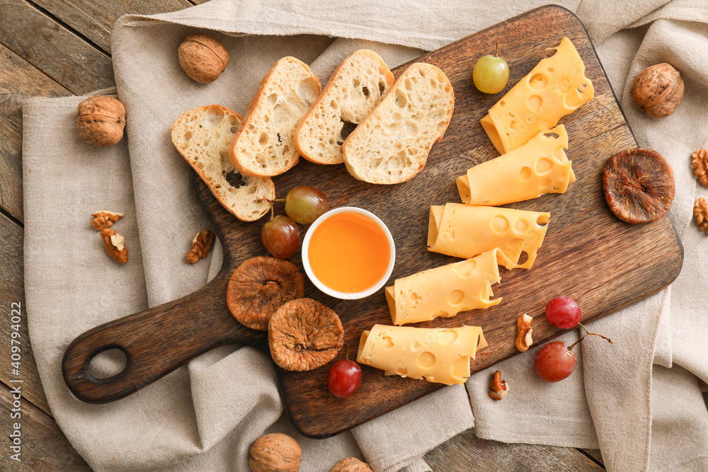 Composition with pieces of tasty cheese and grapes on wooden background