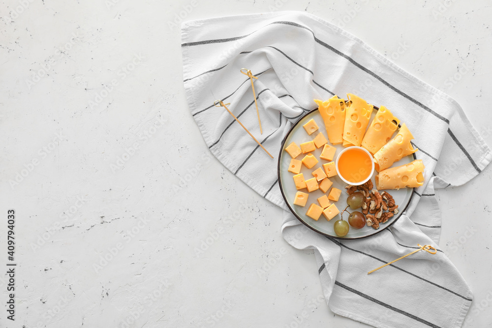 Plate with pieces of tasty cheese and grapes on light background