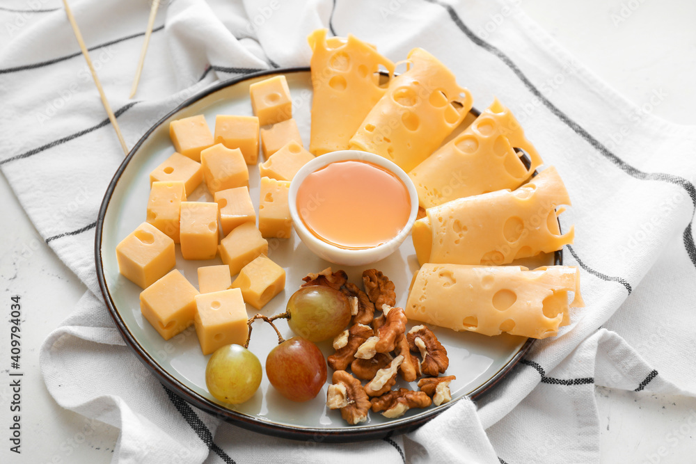 Plate with pieces of tasty cheese and grapes on table