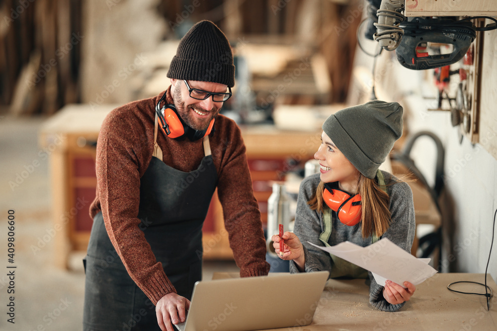 Cheerful joinery owners discussing project on laptop