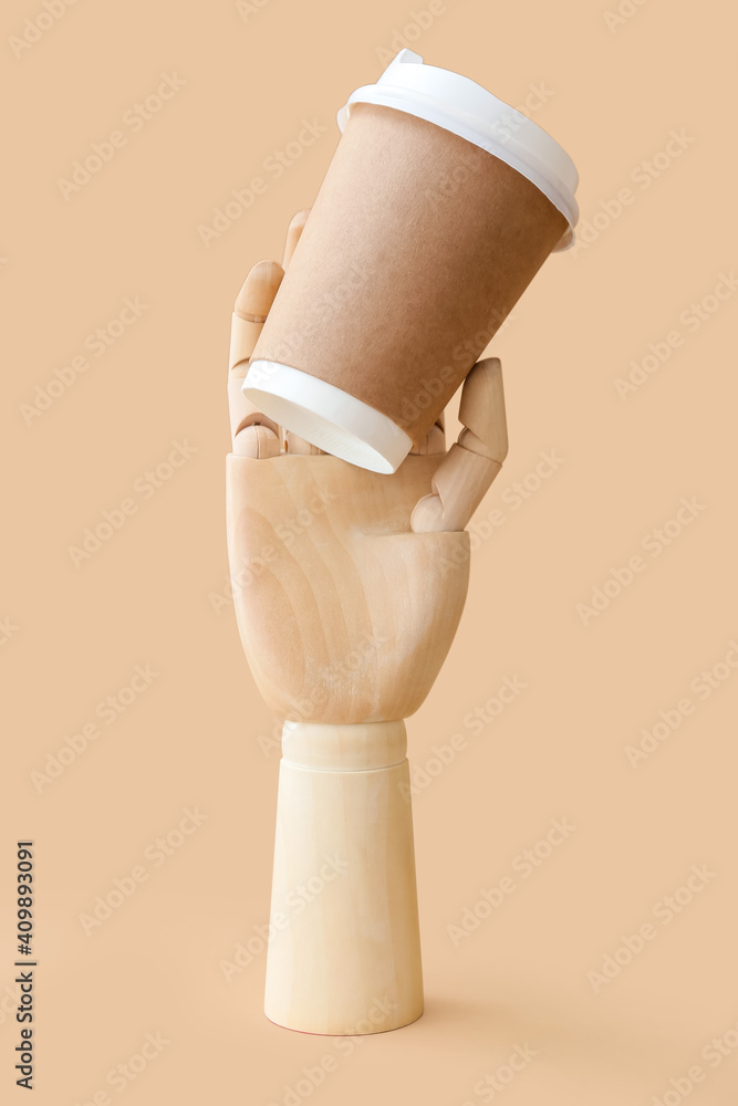 Wooden hand with cup of coffee on color background