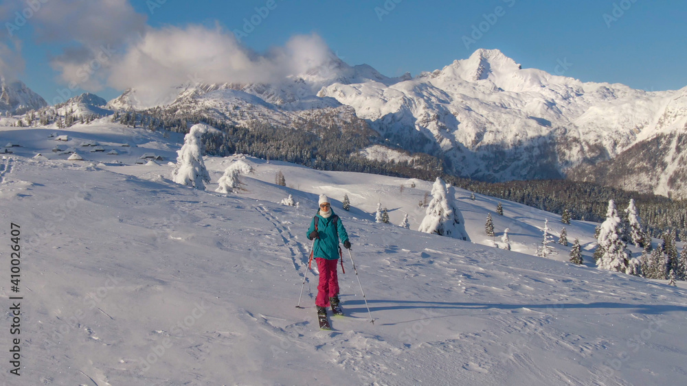 航空：冬季的Velika Planina，女性滑雪游客徒步穿越雪地。