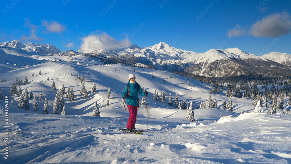 无人机：一名女子沿着雪山徒步旅行，俯瞰群山。