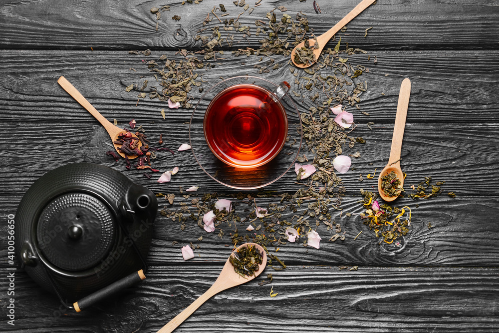 Composition with teapot, cup and dry tea leaves on wooden background