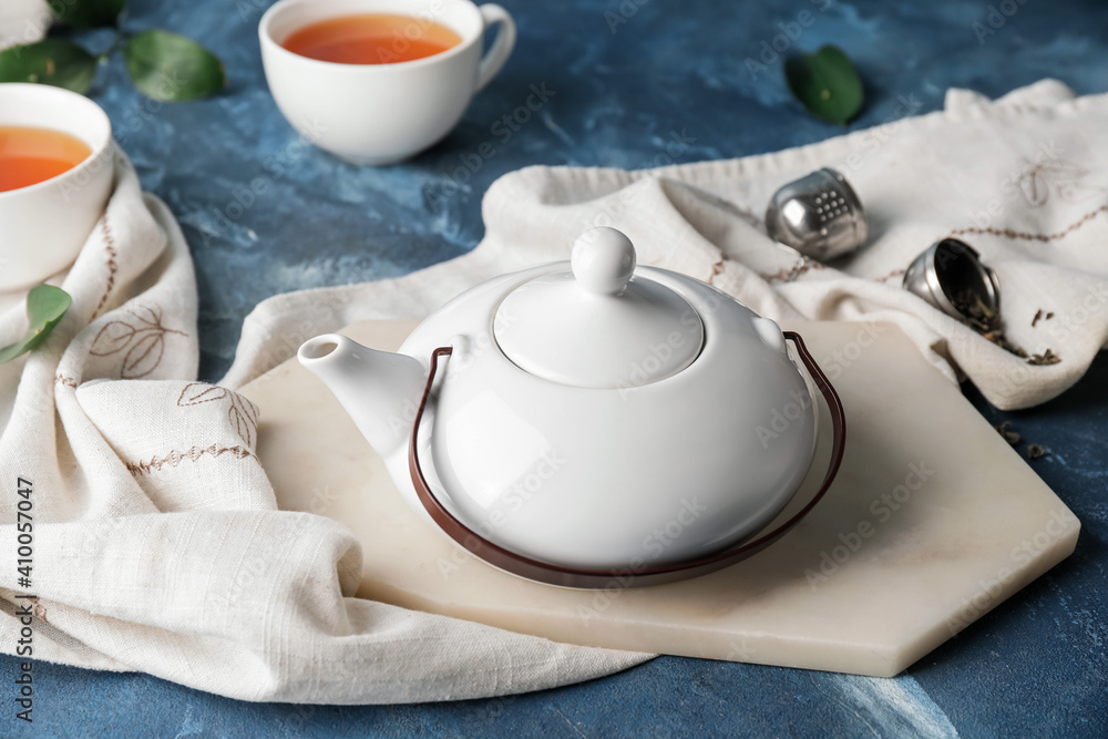 Teapot and cups of tea on color background