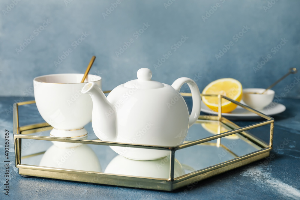 Teapot and cup of tea on color background